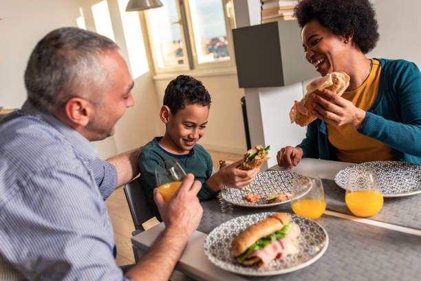 istock Smiling mixed race family sitting at the kitchen table having breakfast at home. 1342248997