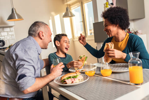 istock Smiling mixed race family sitting at the kitchen table having breakfast at home. 1342249807