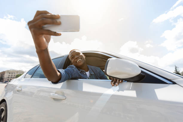 Emotional guy taking selfie on phone while travelling by car