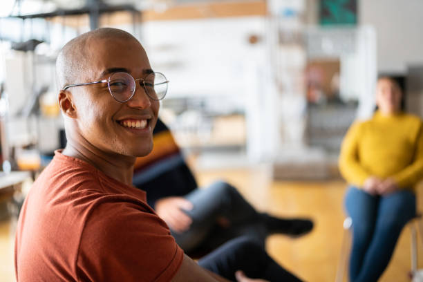 porträt eines jungen mannes in gruppentherapie bei einem coworking - half staff stock-fotos und bilder