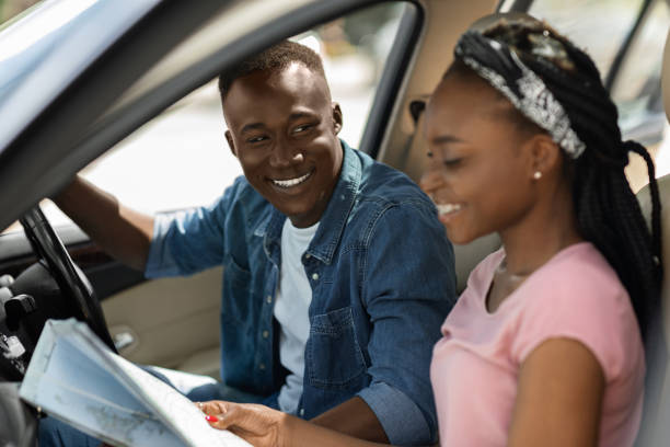 istock Excited afro american couple travellers looking at map while driving 1342252300