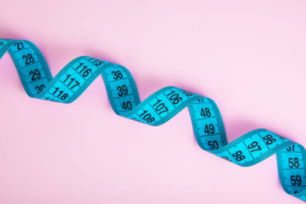 istock Bright colorful tape measure on pink background with copyspace 1342252390