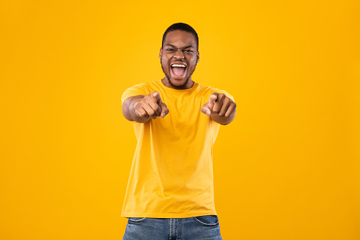Hey, You. Emotional African American Man Pointing Fingers With Both Hands Looking At Camera And Shouting Standing On Yellow Studio Background. You're Next, I Choose You Concept
