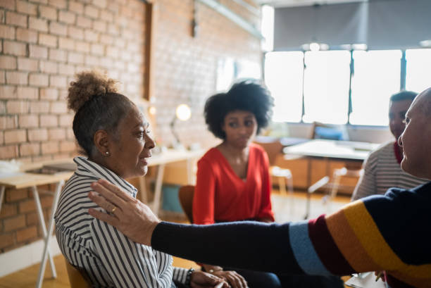 мужчина утешает позую женщину в групповой терапии - discussion women circle therapy стоковые фото и изображения