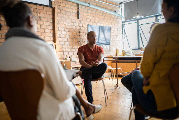 istock Young man talking in group therapy at a coworking 1342253549