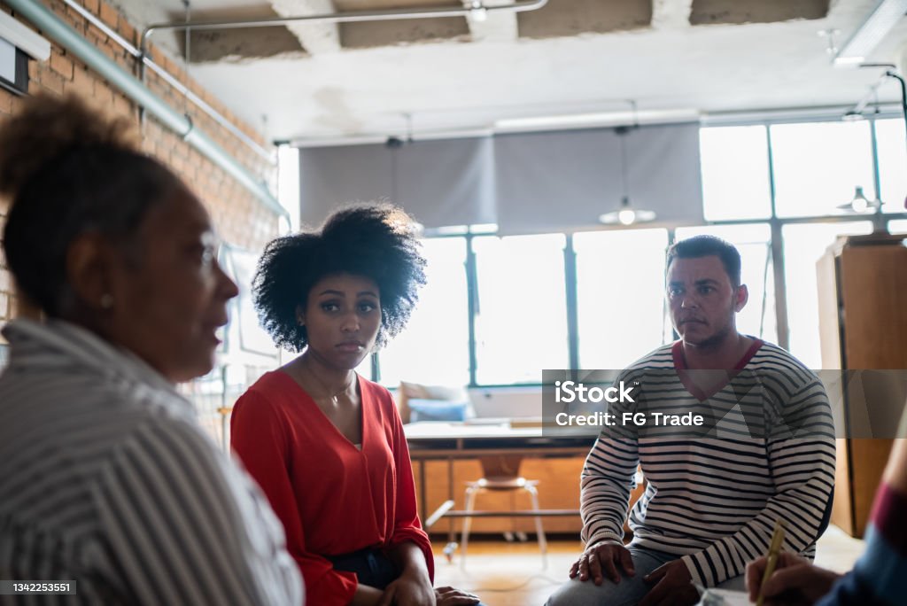 Senior woman talking in group therapy at a coworking - including a transgender man Senior woman talking in group therapy at a coworking Group Therapy Stock Photo