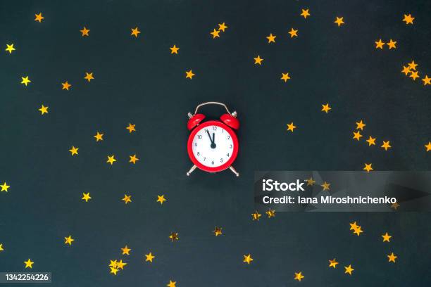 Christmas Composition With Red Alarm Clock Twelve And Golden Stars Confetti On Black Background New Year Christmas Holiday Stock Photo - Download Image Now
