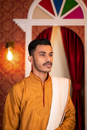 Portrait of young male Model wearing kurta pajama standing with classic vintage interior in studio lighting. Wedding Religious Lifestyle Festive Fashion.
