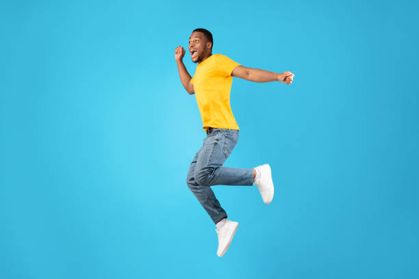 istock Joyful African Man Jumping And Shouting In Mid-Air, Blue Background 1342254483