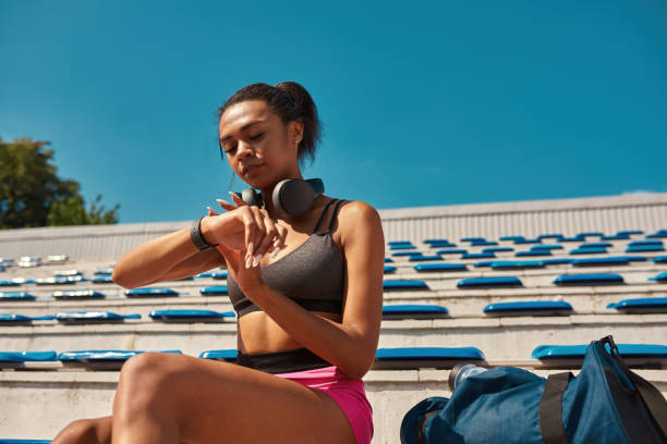 istock Young sportswoman checking results after training using smartwatch while resting on the stadium seat outdoors 1342254639