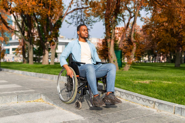 istock Paraplegic black guy in wheelchair going down ramp on on walk at park in autumn, using impaired friendly facilities 1342254723