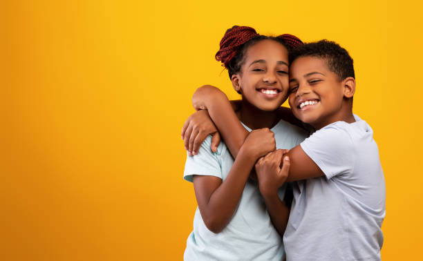 emotionaler afroamerikanischer bruder und schwester, die sich umarmen und lächeln - people child twin smiling stock-fotos und bilder