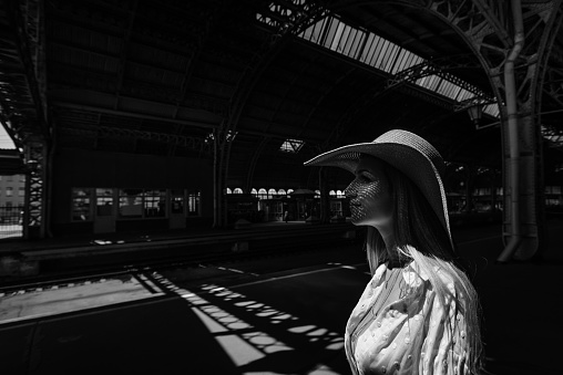 Traveler at the train station with a large straw hat and a large bag