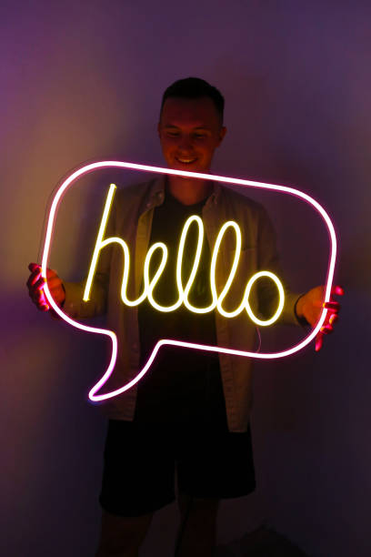 istock Handsome young man holding pink and yellow neon sign hello. 1342260361