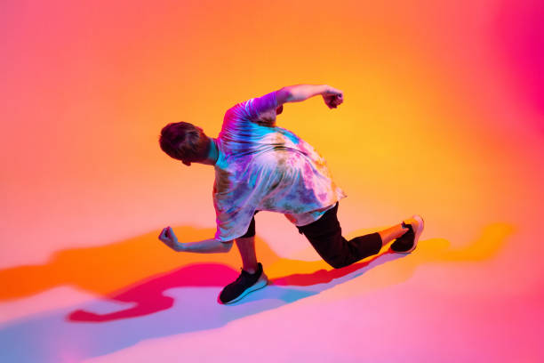 istock Top view image of young man dancing hip-hop isolated over gradient yellow pink studio background in neon light 1342265663
