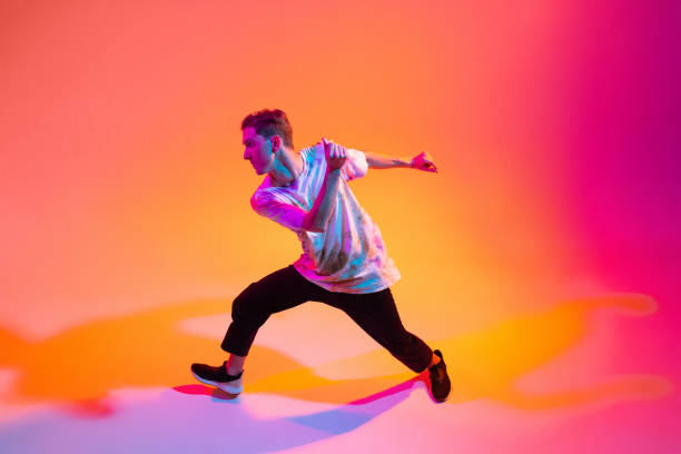 istock Street style dancer. Young boy dancing hip-hop isolated over gradient yellow pink studio background in neon light 1342265667