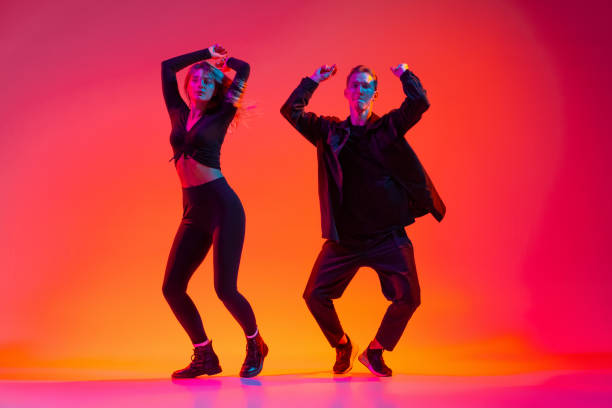 istock Active young man and woman dancing hip-hop isolated on gradient pink studio background in neon light 1342265672