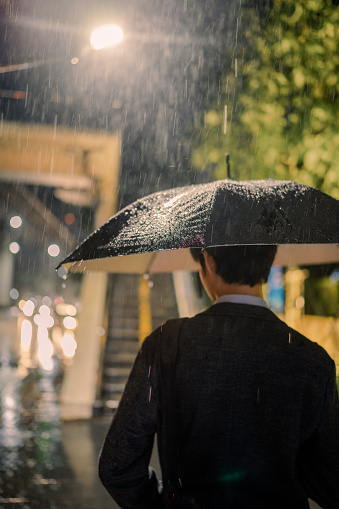 Company employees work overtime causing late work and rain, but luckily he carries an umbrella.