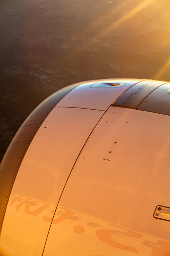 Partial view of an airplane engine during a sunset flight.