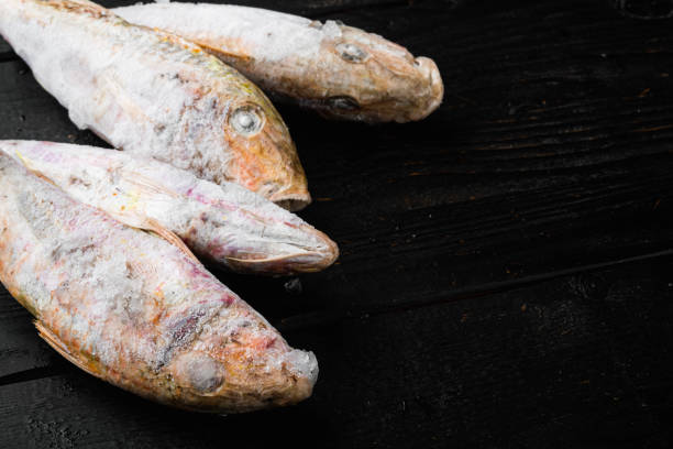 istock Frozen mullet or sultanka fish, on black wooden table background , with copy space for text 1342269359