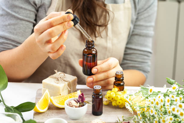 mujer realizando investigación cosmética profesional. concepto de ingredientes orgánicos naturales en dermatología. aceite esencial, extracto de hierbas, frutas, verduras. cuerpo hidratante natural, cuidado facial - aceites esenciales fotografías e imágenes de stock