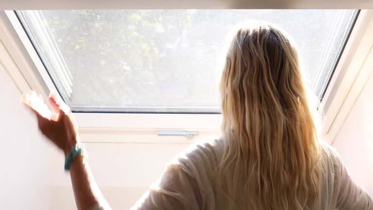 Woman raised blind over skylight window