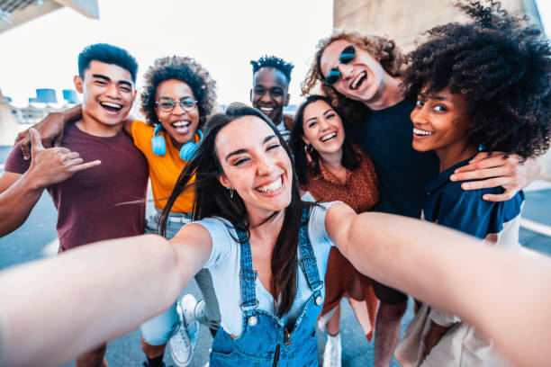 multicultural happy friends having fun taking group selfie portrait on city street - multiracial young people celebrating laughing together outdoors - happy lifestyle concept - tourists couple barcelona imagens e fotografias de stock