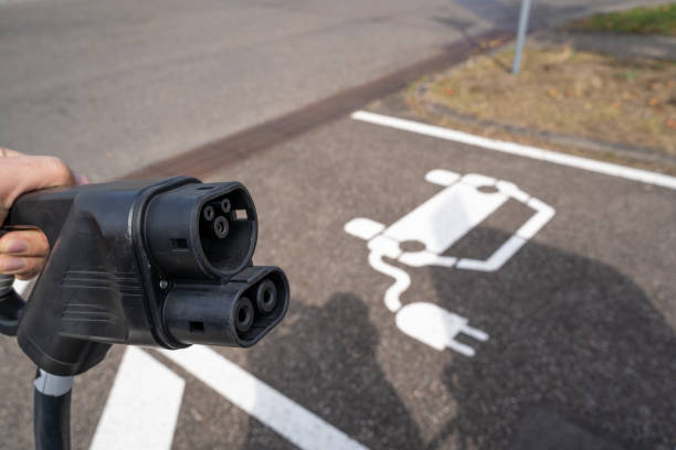istock Hand holds electric plug at an electric charging station 1342273885