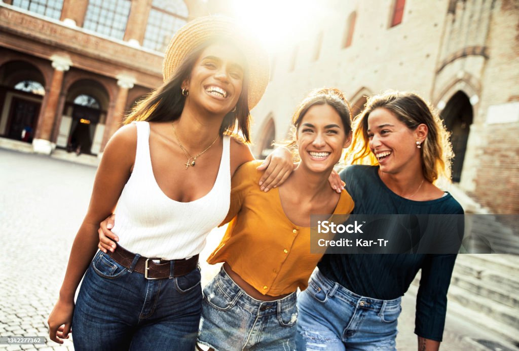 Three young diverse women having fun on city street outdoors - Multicultural female friends enjoying a holiday day out together - Happy lifestyle, youth and young females concept Friendship Stock Photo