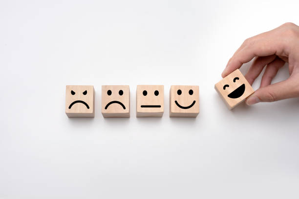 istock Hand holding smile face symbol on wooden cube blocks on white background. Customer service evaluation and satisfaction survey concepts. Service rating, ranking, customer review 1342277378