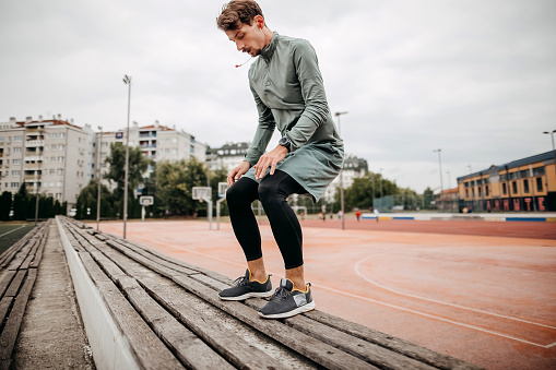 Man warms up on the athletic track with pre-workout exercises
