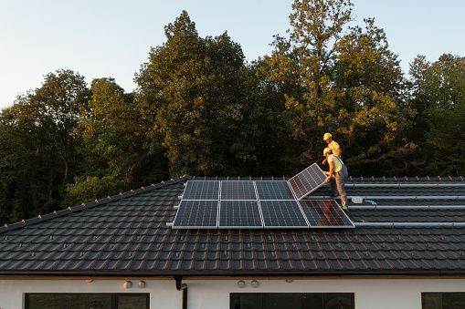 Dos trabajadores instalando paneles solares en una casa moderna. photo