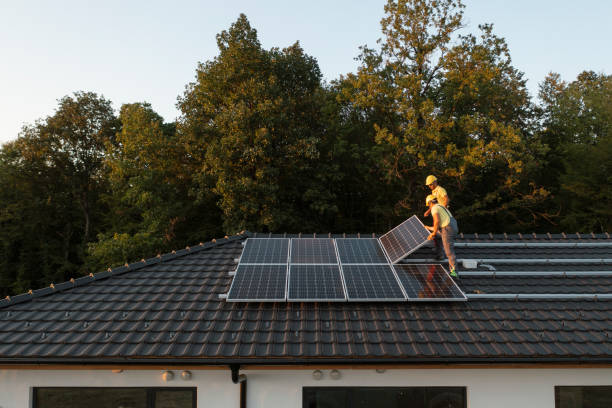 dos trabajadores instalando paneles solares en una casa moderna. - energía solar fotografías e imágenes de stock