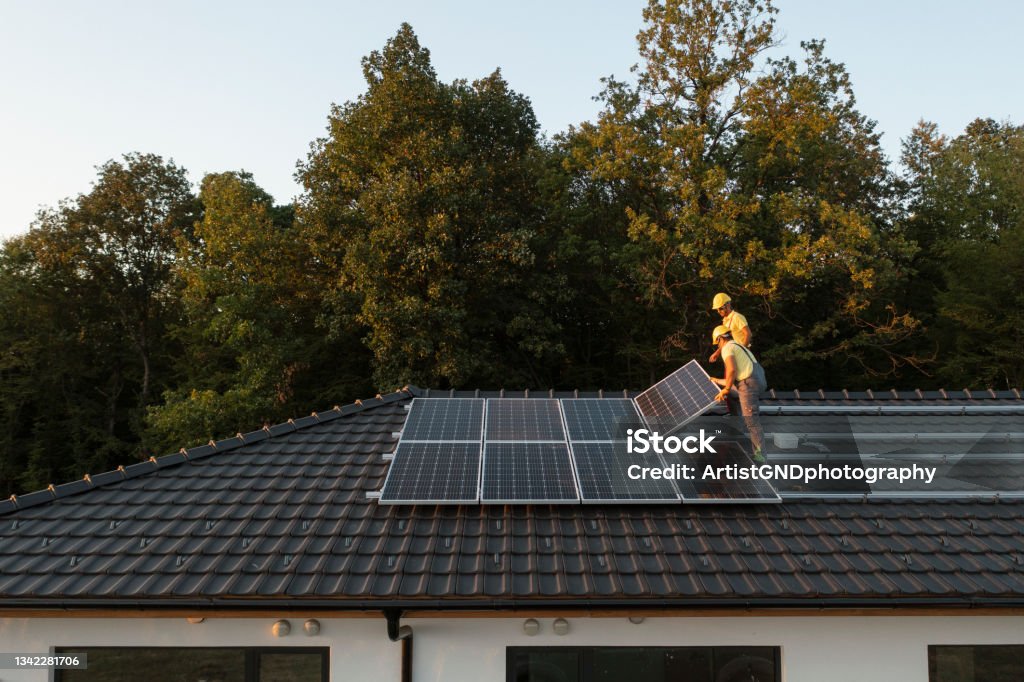 Two Workers Installing Solar Panels On Modern House. Two Professionalists Installing Solar Panels On A   Roof Of A Modern House. Solar Energy Stock Photo