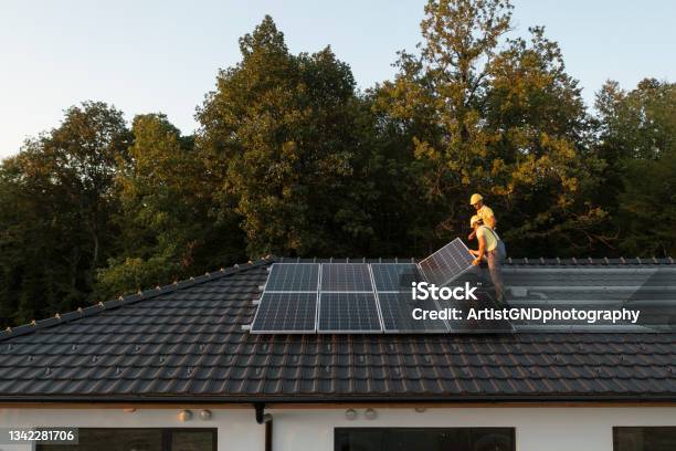 Two Workers Installing Solar Panels On Modern House Stock Photo - Download Image Now