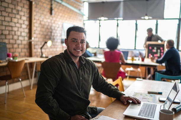 Portrait of a transgender man using the laptop at a coworking Portrait of a transgender man using the laptop at a coworking transgender person in office stock pictures, royalty-free photos & images