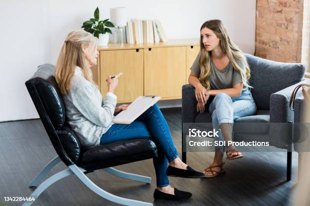 Mature Therapist Shakes Finger And Lectures Young Female Client Stock Photo - Download Image Now