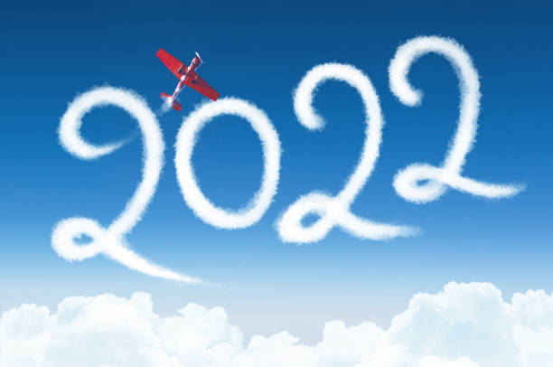 istock Happy New year 2022 concept on the background below cloudscape. Drawing by passenger light-engine, turboprop airplane white vapor contrail in sky. 1342286244