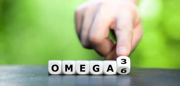 Symbol for healthy food. Hand turns dice and changes the expression "Omega 6" to "Omega 3".