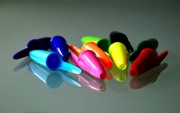 colorful plastic ballpoint pen caps in abstract view on glass surface stock photo