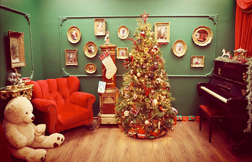Christmas tree, cozy red armchair, fireplace, piano , gifts and toys in the vintage living room. Home interior background for winter  Holidays