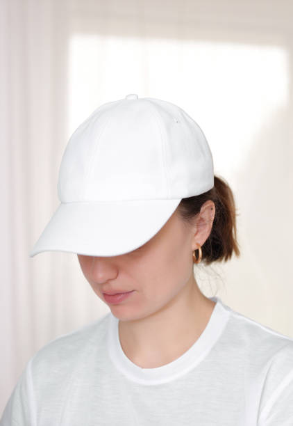 istock Female model wearing a white baseball cap. White cap mockup, template for picture, text or logo. Girl holding visor of cap. Free space, copy space. 1342313125