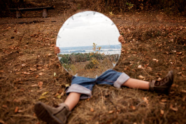 A girl having fun and experiment with big round mirror among beautiful fall orange forest, outdoor creative portrait, autumn mood board