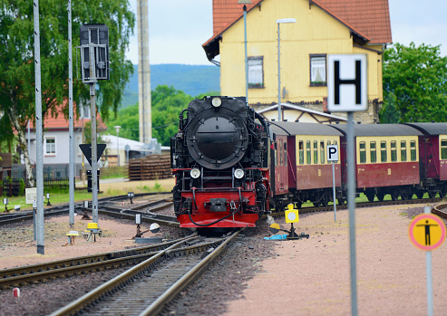 Retro steam train arrives to the station wooden platform. Ruskeala Mountain Park. Republic of Karelia. Russia.