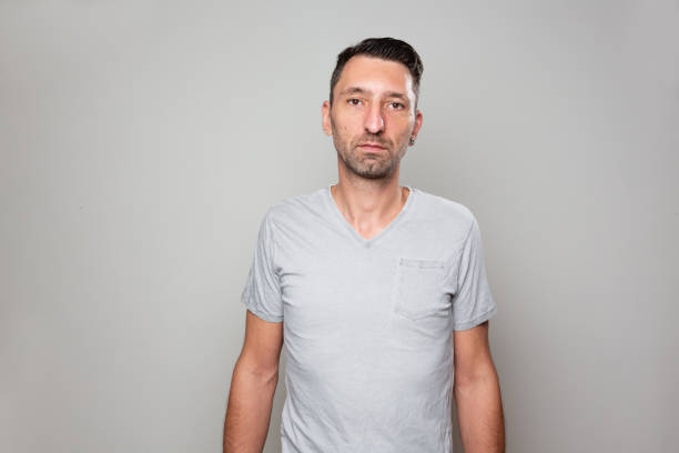 Studio shot of a midadult an with short beard and short black hair, wearing a grey t-shirt