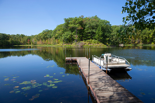 Small lake in northern Minnesota with a dock and pontoon boat on a sunny clear day