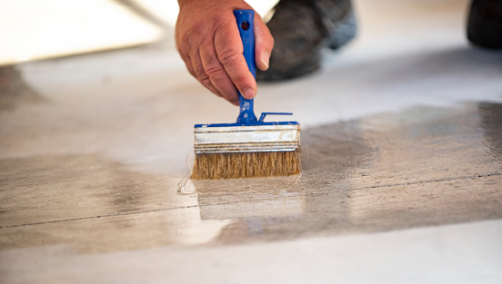 Manual worker painting concrete floor for protection