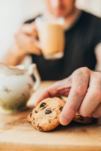 istock Man with an appetite eating chocolate chip cookies with tea 1342323958