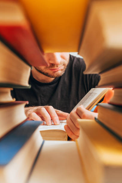 istock A man reading through a frame of stacked books 1342324268
