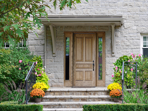 Front steps of stone house with wood grain front door and flower pots
